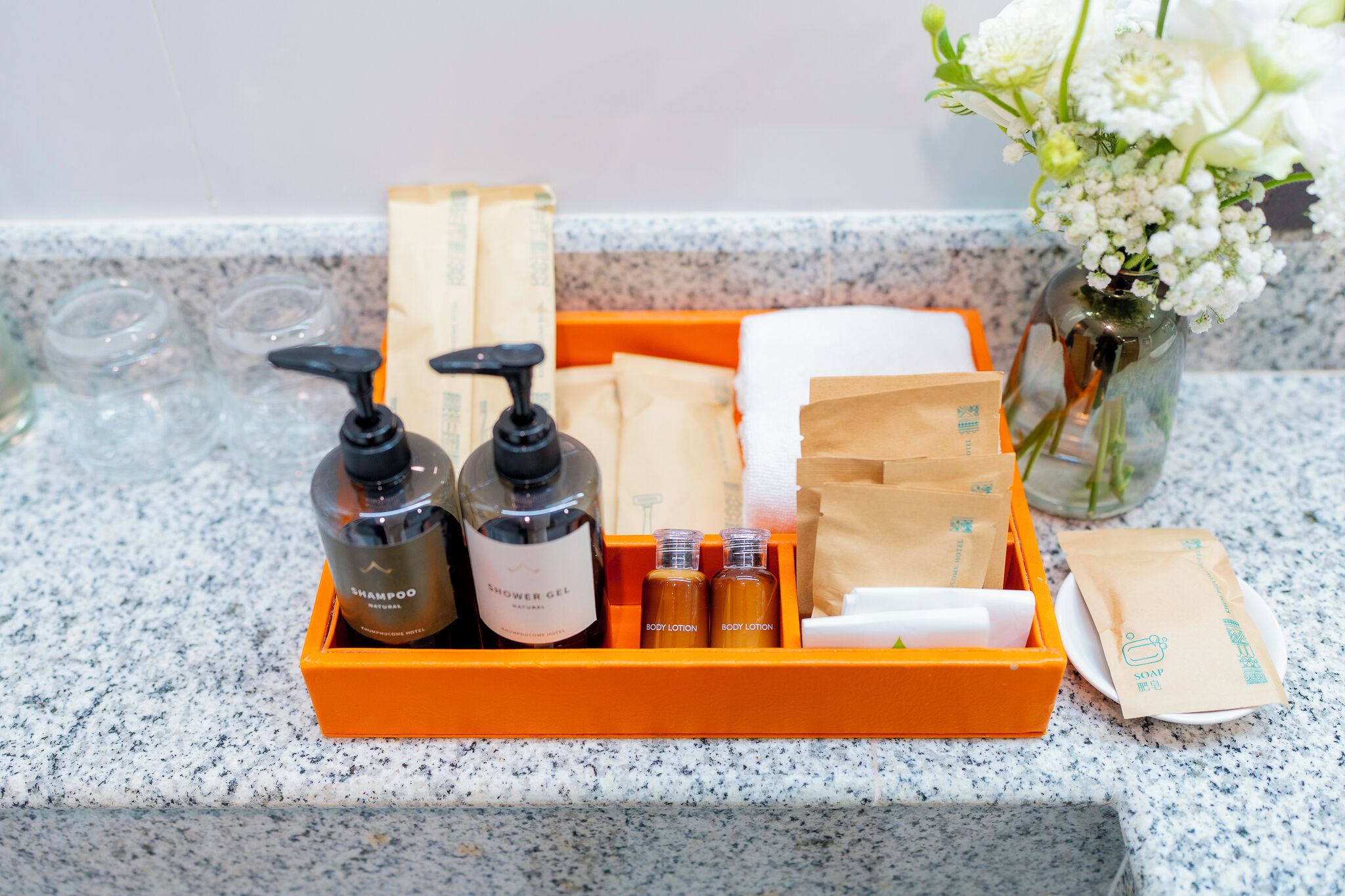 A bathroom counter with a tray containing toiletries including shampoo, shower gel, and body lotion.