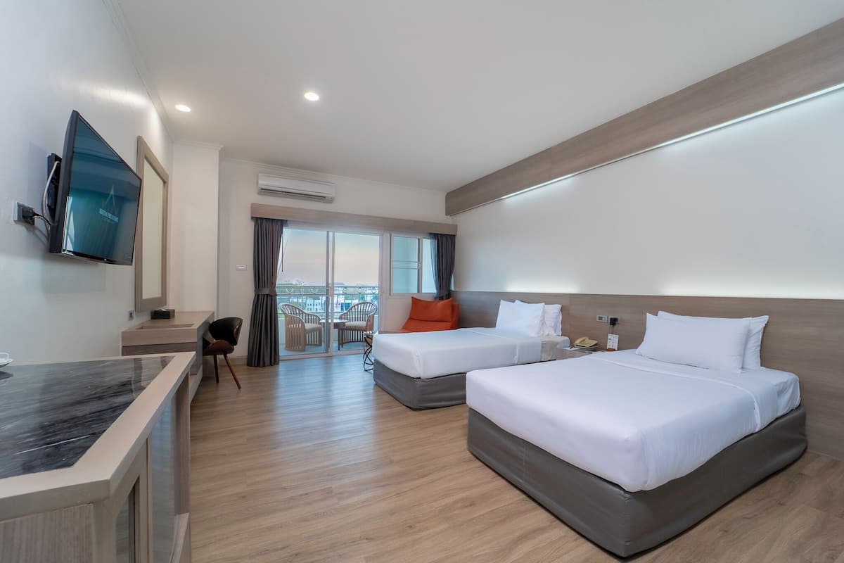 Een hotelkamer met twee bedden, een bureau, een televisie en een balkon met uitzicht.