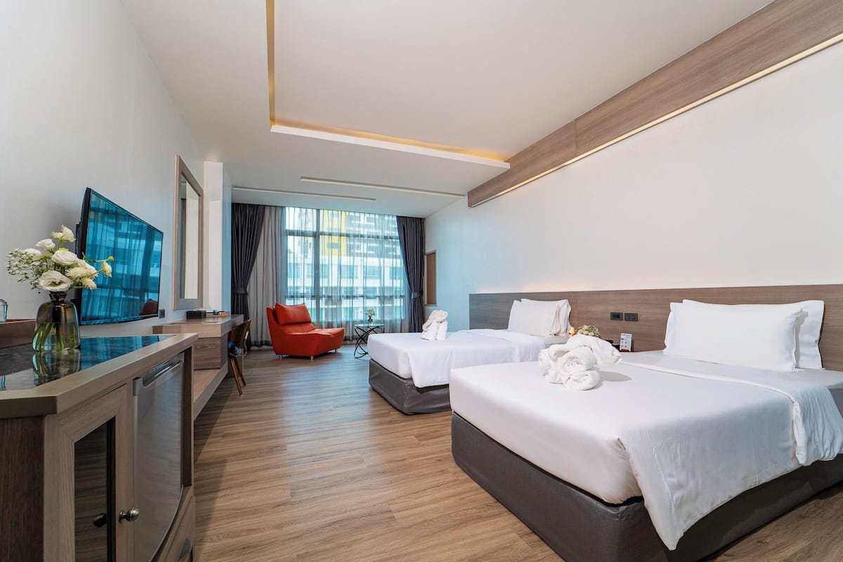 Een hotelkamer met twee bedden, een televisie, een bureau met een vaas en uitzicht op het omliggende landschap.