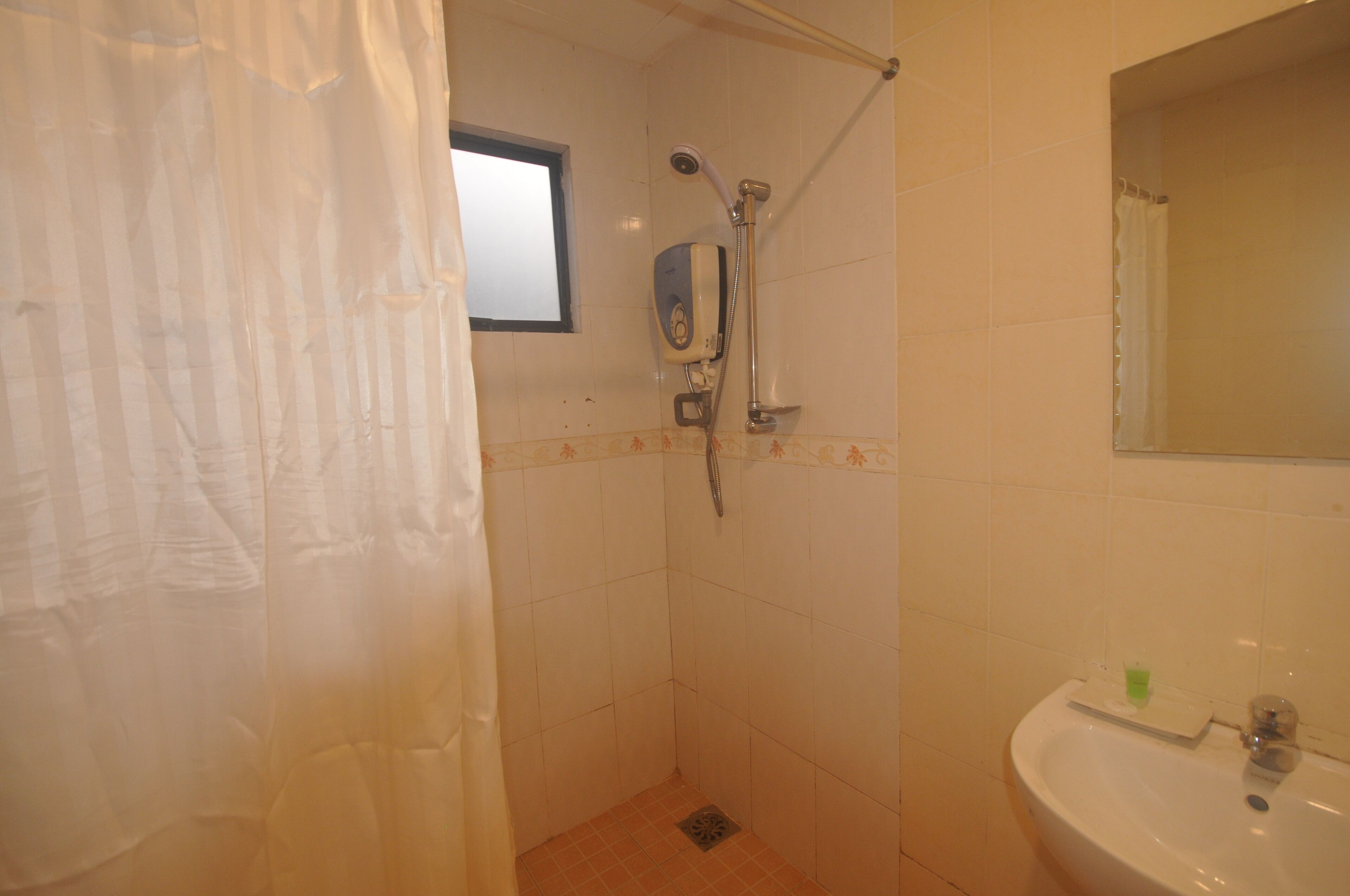 Ein Badezimmer mit Dusche, Waschbecken und Fenster.