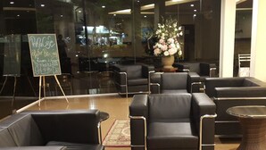 Un espace de détente moderne avec des canapés et des fauteuils en cuir, une table centrale et un panneau d’affichage en forme d’ardoise servant de menu.