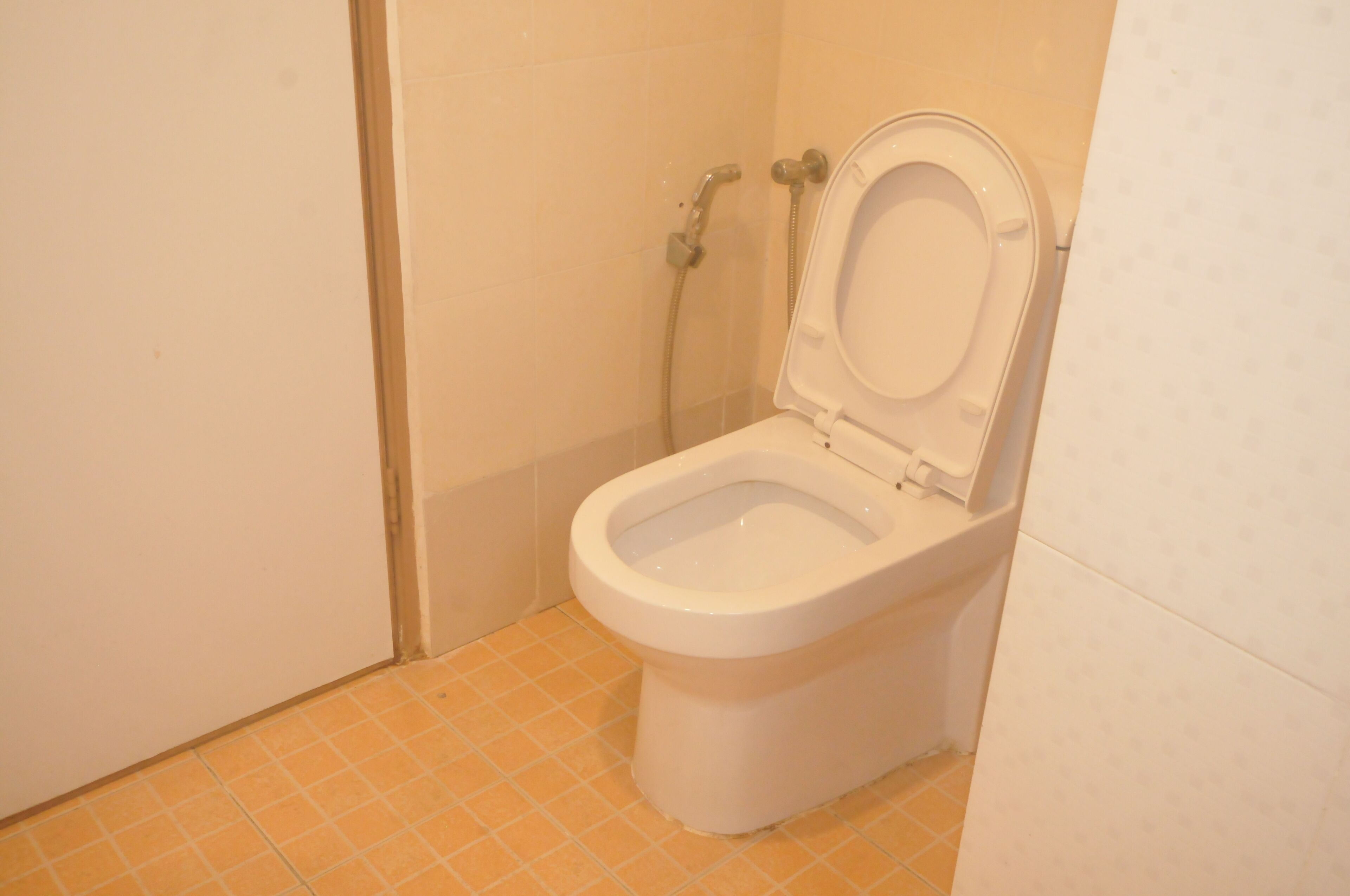 A small bathroom with a toilet, a shower, and a tiled floor.