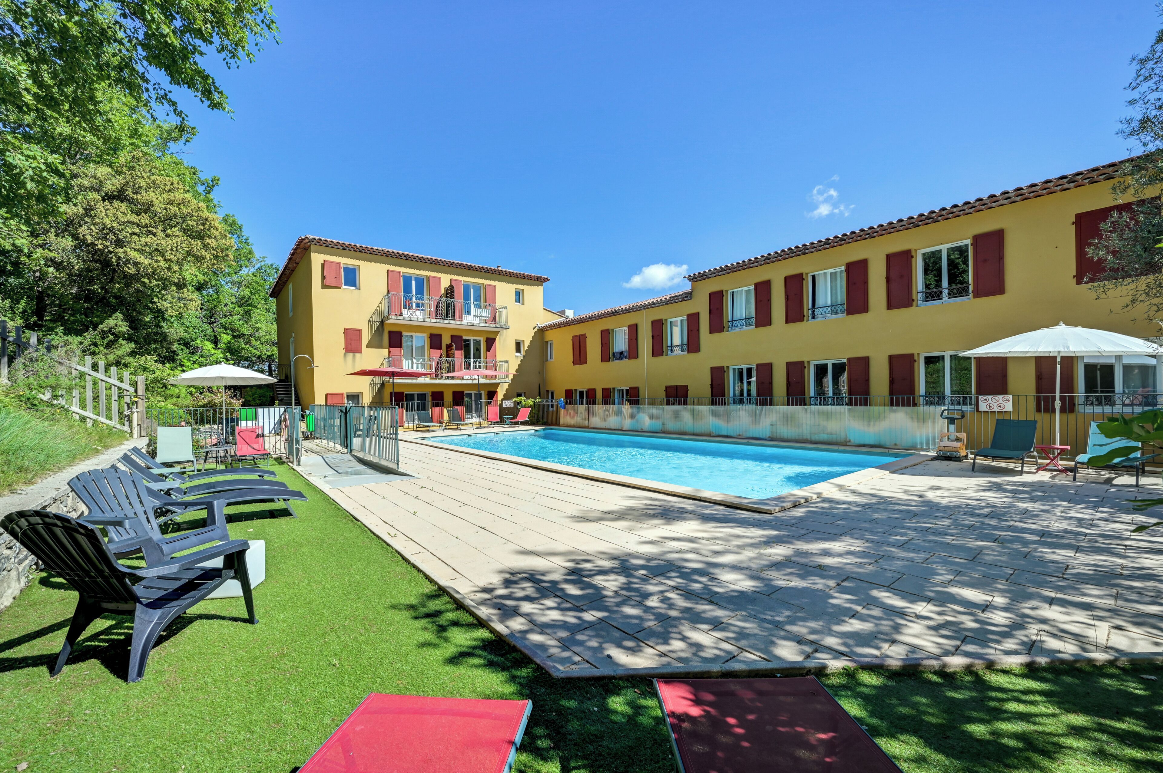 A swimming pool with lounge chairs and a building with balconies.