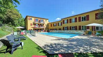 A swimming pool with lounge chairs and a building with balconies.