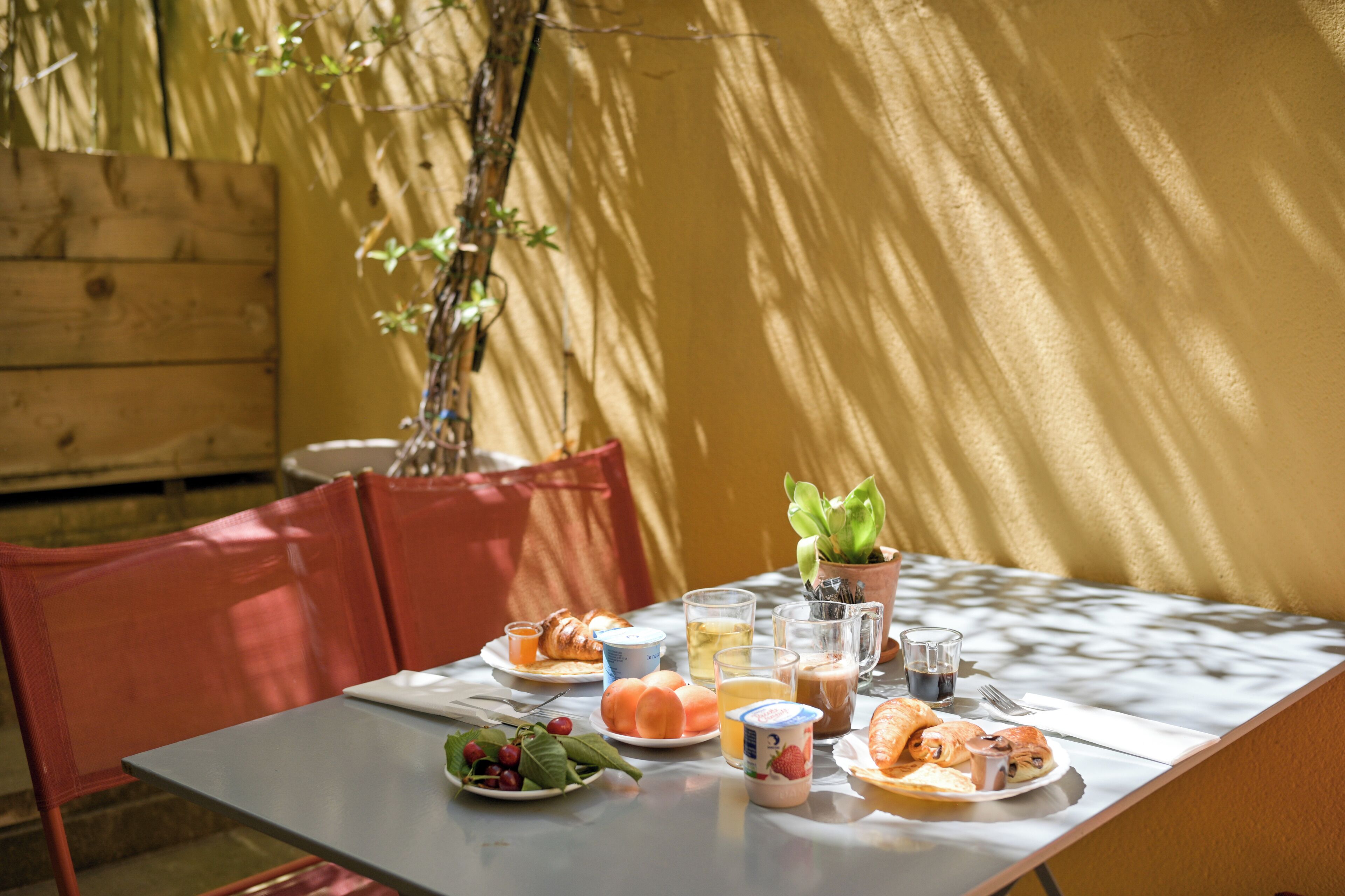 A table set for breakfast with croissants, fruit, and beverages.
