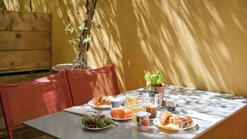 A table set for breakfast with croissants, fruit, and beverages.