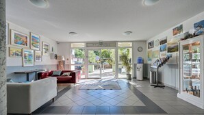 A hotel lobby with a reception desk, a red sofa, framed pictures on the walls, and a water dispenser.
