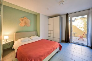 Hotelkamer met een bed, nachtkastje, garderobe en een glazen schuifdeur naar een terras.