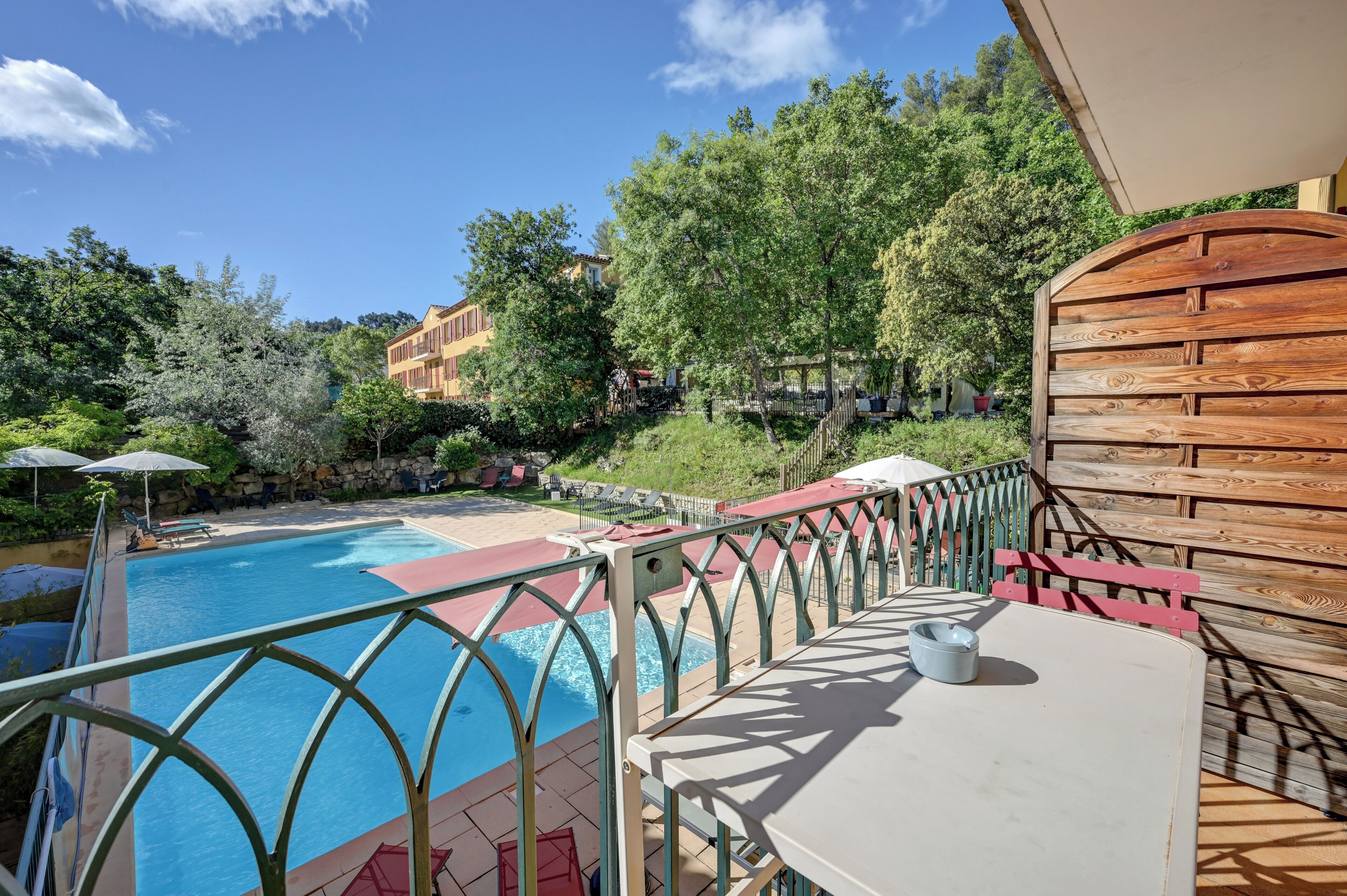 A pool area with a wooden deck, lounge chairs, and a table.