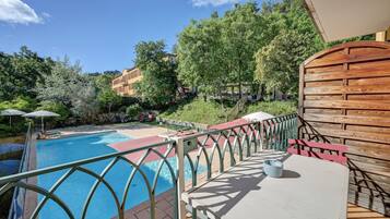 A pool area with a wooden deck, lounge chairs, and a table.