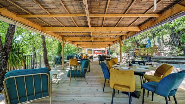 An outdoor covered patio area with wooden flooring, metal-framed chairs, and tables.