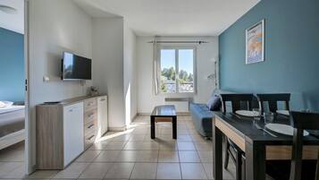 A modern kitchen with a TV, a dining area with a table and chairs, and a sofa.