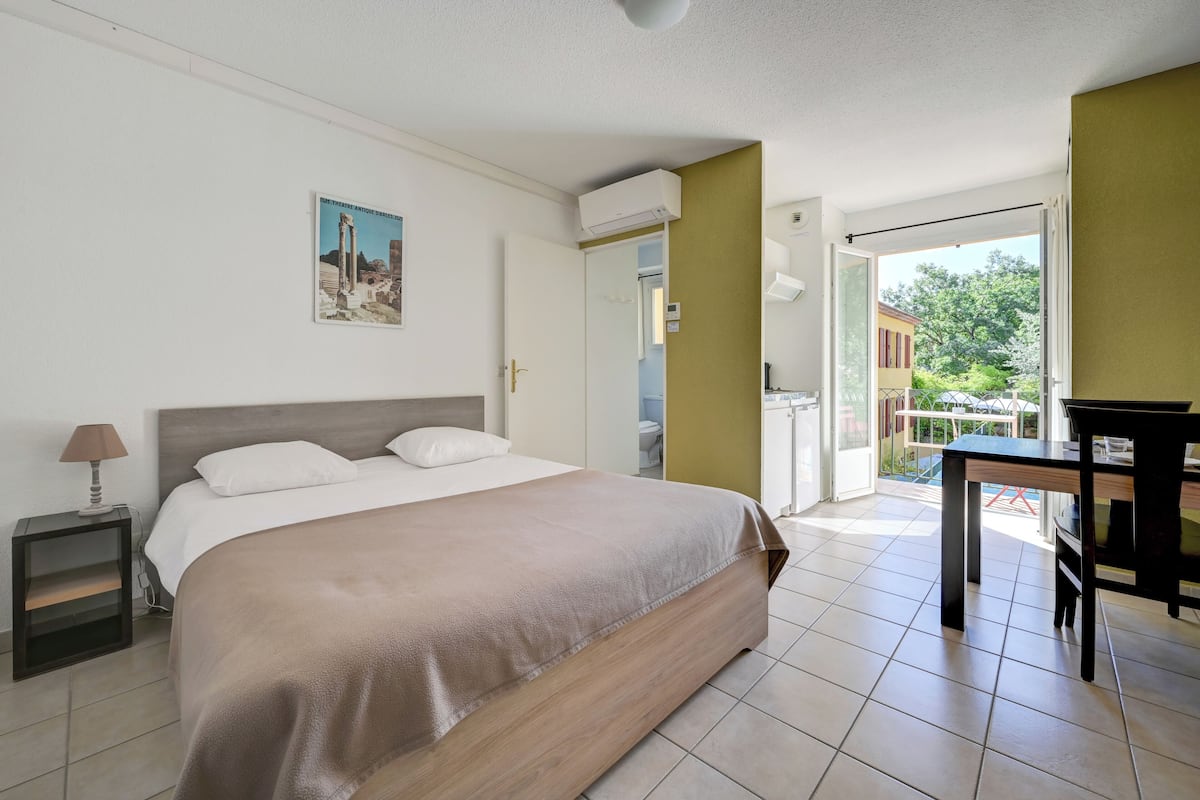 A bedroom with a bed, bedside table, lamp, and a painting on the wall.