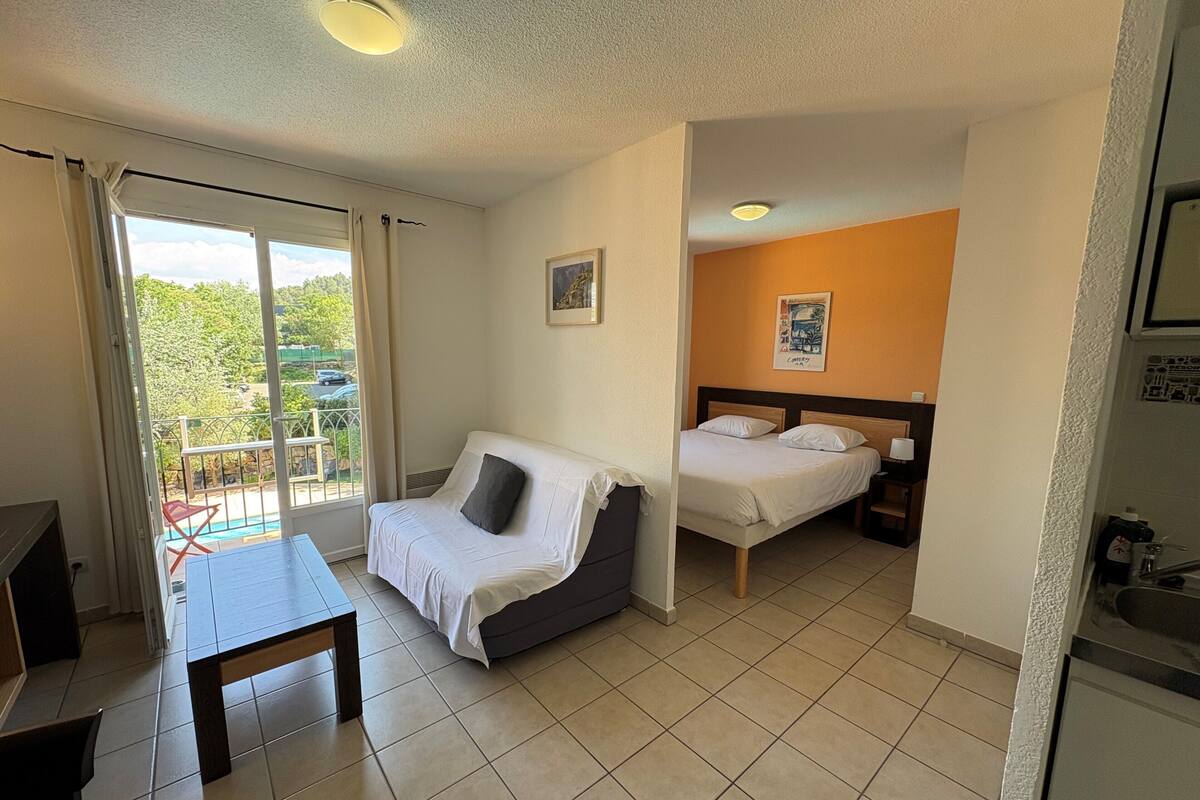 A hotel room with a bed, a sofa, a table, and a balcony with a view.
