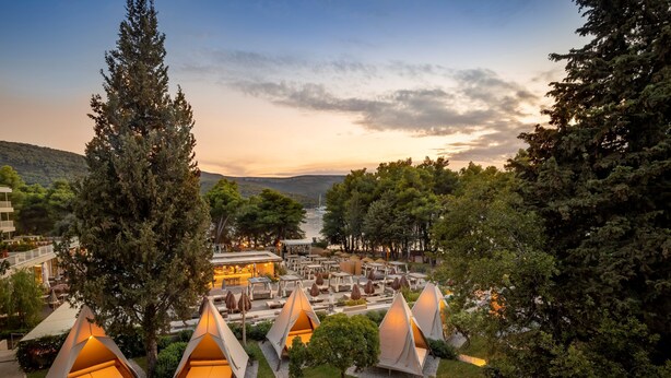 Ein Resort mit mehreren Zelten in Baumform, einem Essbereich und Blick auf die Berge.
