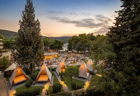 A resort with multiple tree-shaped tents, a dining area, and a view of the mountains.