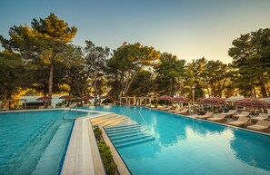 Una piscina al aire libre, sombrillas, tumbonas