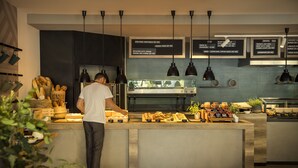 A modern kitchen with a chef preparing food, a variety of dishes displayed, and a menu board above.
