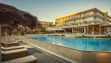 Ett hotell med en swimmingpool, solstolar och en byggnad med balkonger.