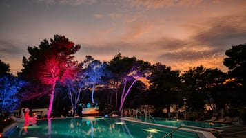 Una piscina al aire libre, sombrillas, sillones reclinables de piscina
