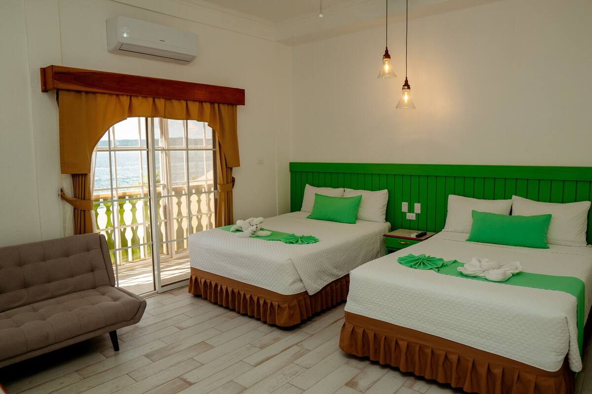 Habitación de hotel con dos camas, un sofá y vista al mar.