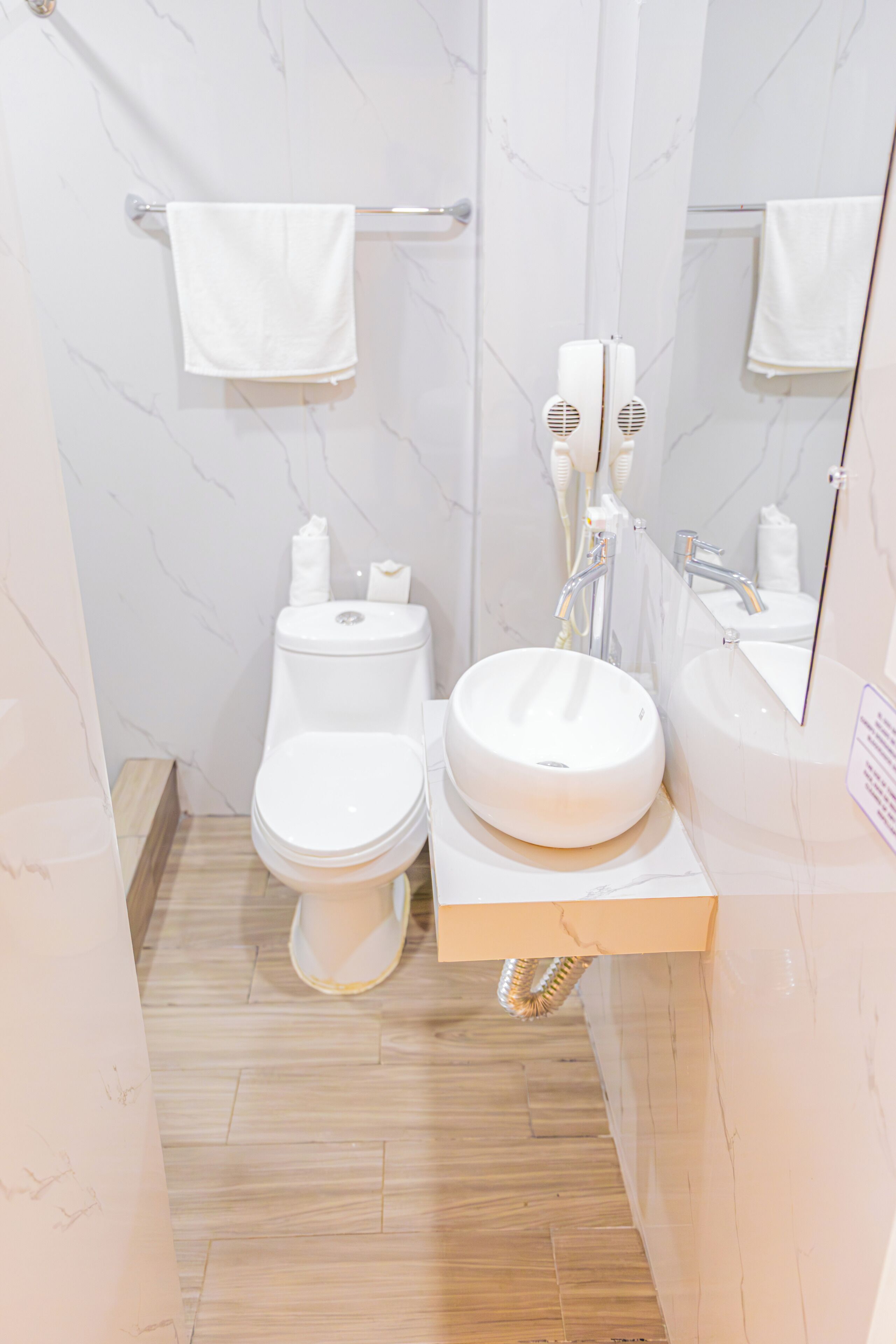 A bathroom with a toilet, sink, and mirror.