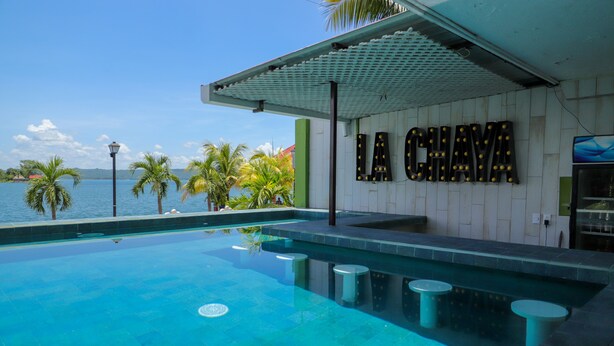 A swimming pool with a view of the sea, a sign reading "LA CHAYA", and a covered area with a pergola. - Hotel Petén (Flores)