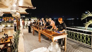 A long wooden table with people standing around it, possibly at a restaurant or bar. - Hotel Petén (Flores)
