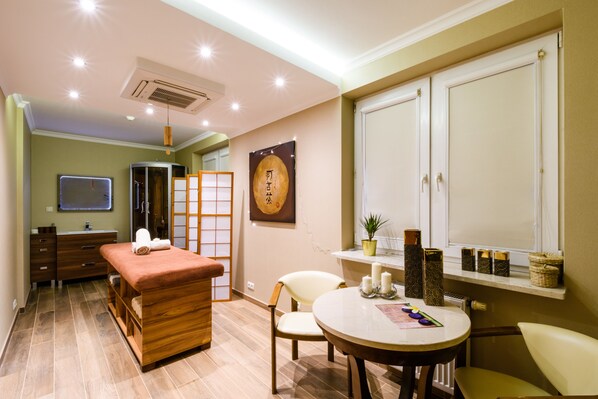 A room with a wooden bench, a round table, a mirror, a shelf with decorative items, and a sliding door.