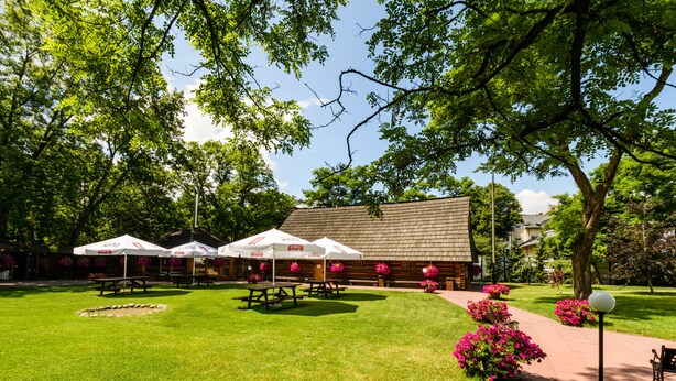 Un patio con mesas de picnic, sombrillas blancas y un edificio con techo inclinado.