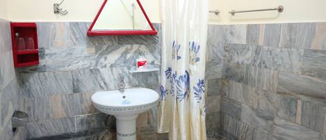 A bathroom with a pedestal sink, a red shelf with glasses, a red and white towel rack, and a shower curtain with a floral pattern.