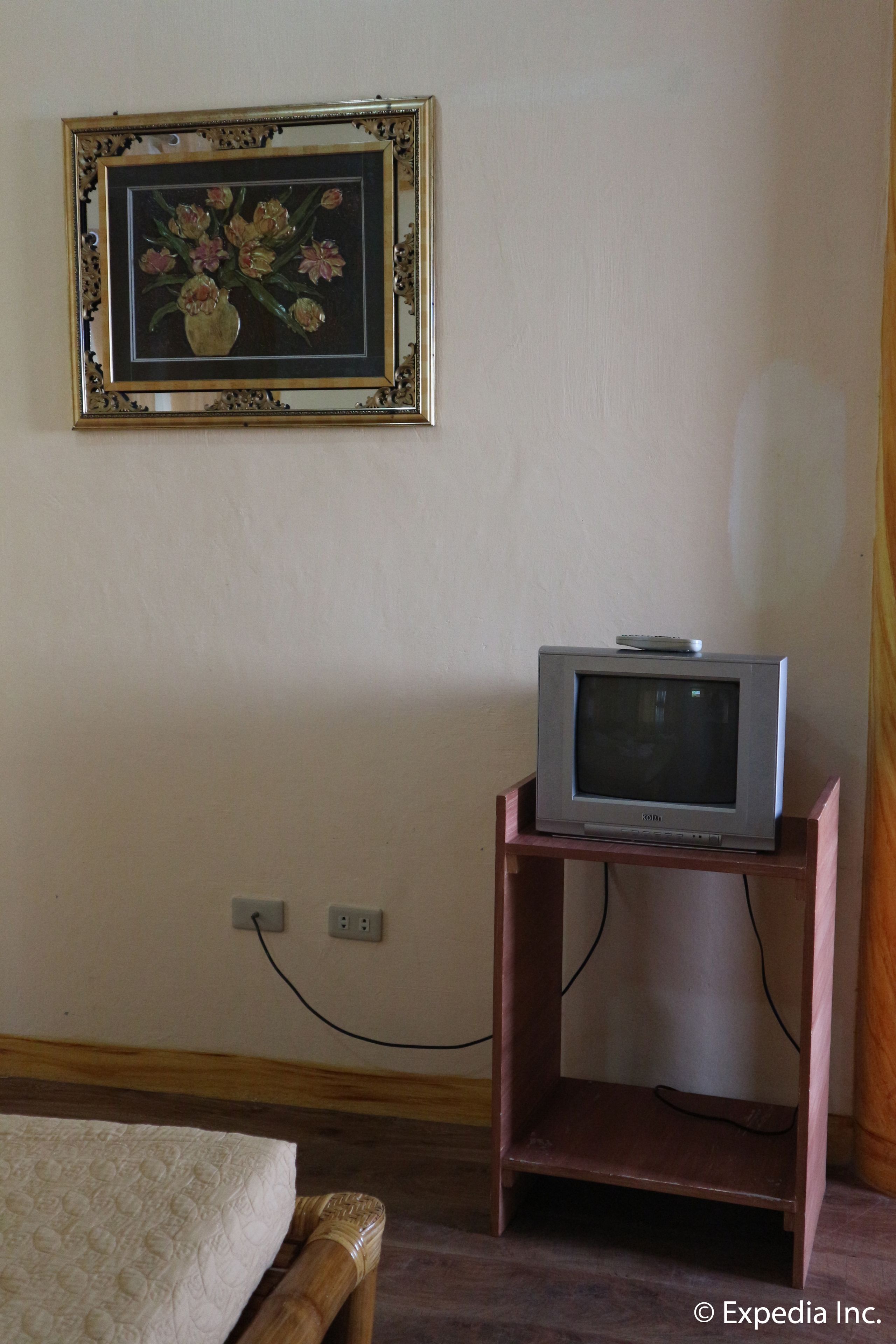 A room with a bed, a framed picture on the wall, and an old television on a wooden stand.