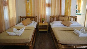 Habitación de hotel con dos camas de madera, ropa de cama color beige y una mesita de noche de madera con una decoración de piña.