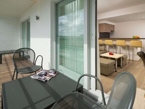 A modern interior with a dining area, kitchen, and a balcony with a table and chairs. - ibis Styles Zeebrugge (Bruges)