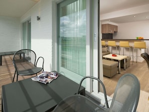 Ein modernes Interieur mit Essbereich, Küche und einem Balkon mit Sitzgelegenheiten.