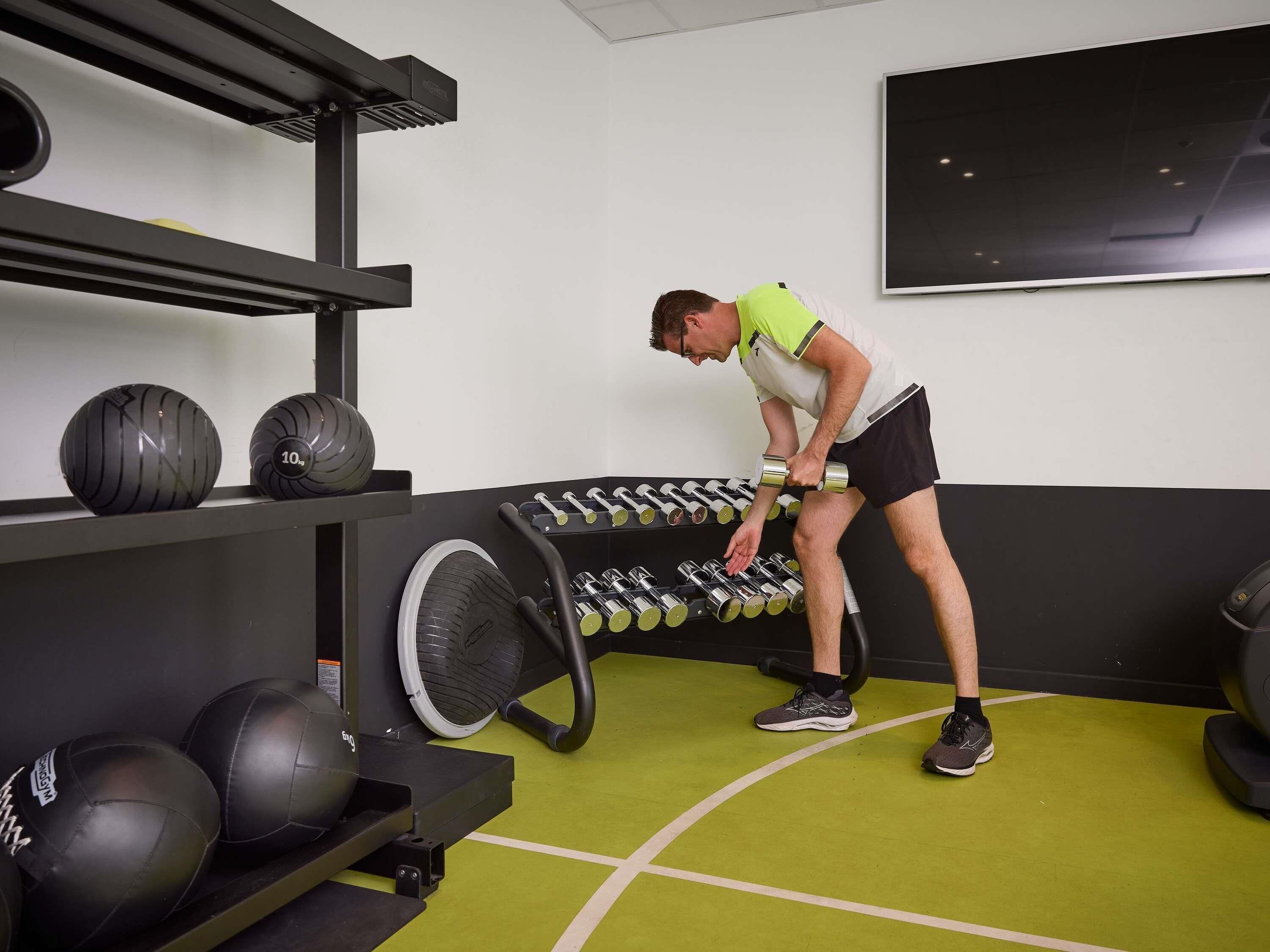 Un gimnasio con equipo de ejercicio, incluyendo mancuernas y balones medicinales.