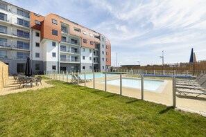 A modern apartment building with a swimming pool, outdoor seating, and a well-maintained lawn. - ibis Styles Zeebrugge (Bruges)