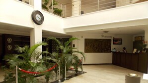 Un hall con mostrador de recepción, un reloj y una obra de arte grande en la pared.