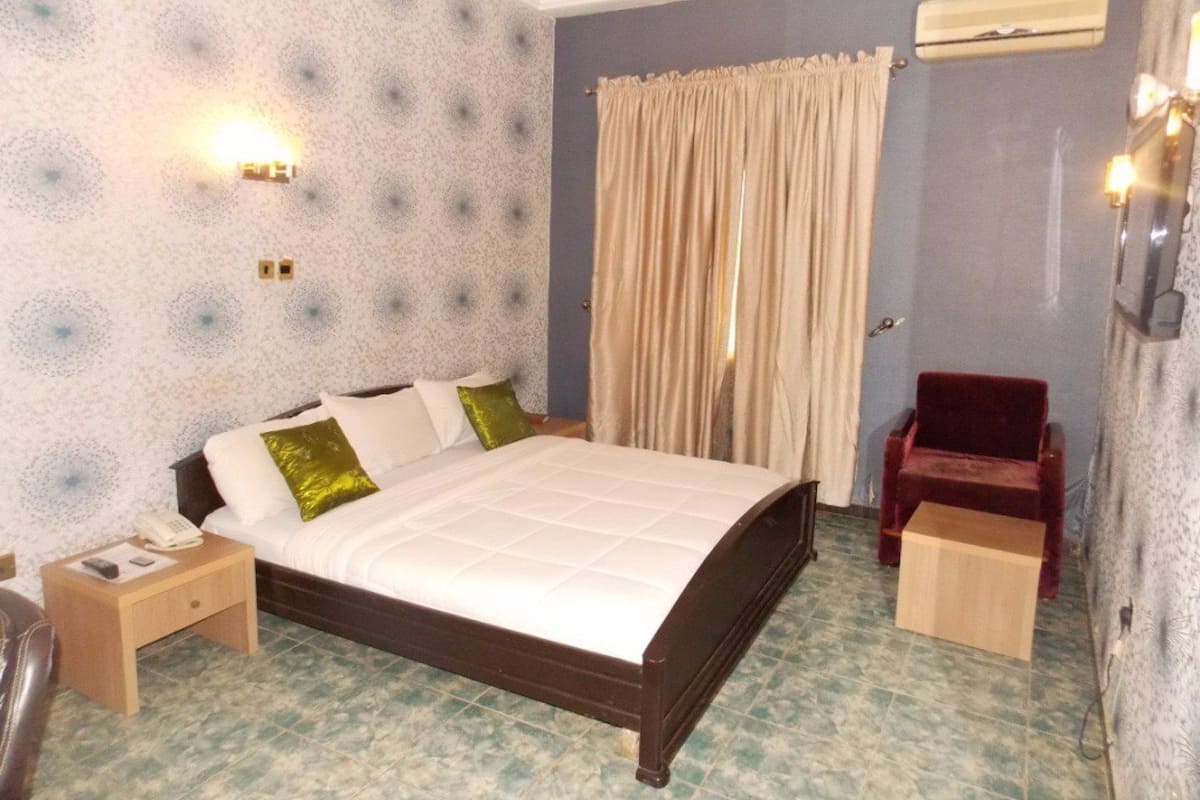 A bedroom with a bed, bedside table, and a red chair.