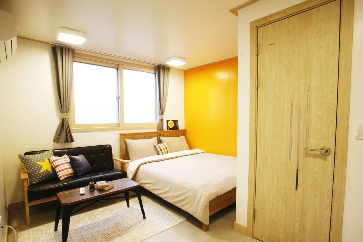 Una camera da letto con un letto, un divano, un armadio in legno, una finestra e un comodino.