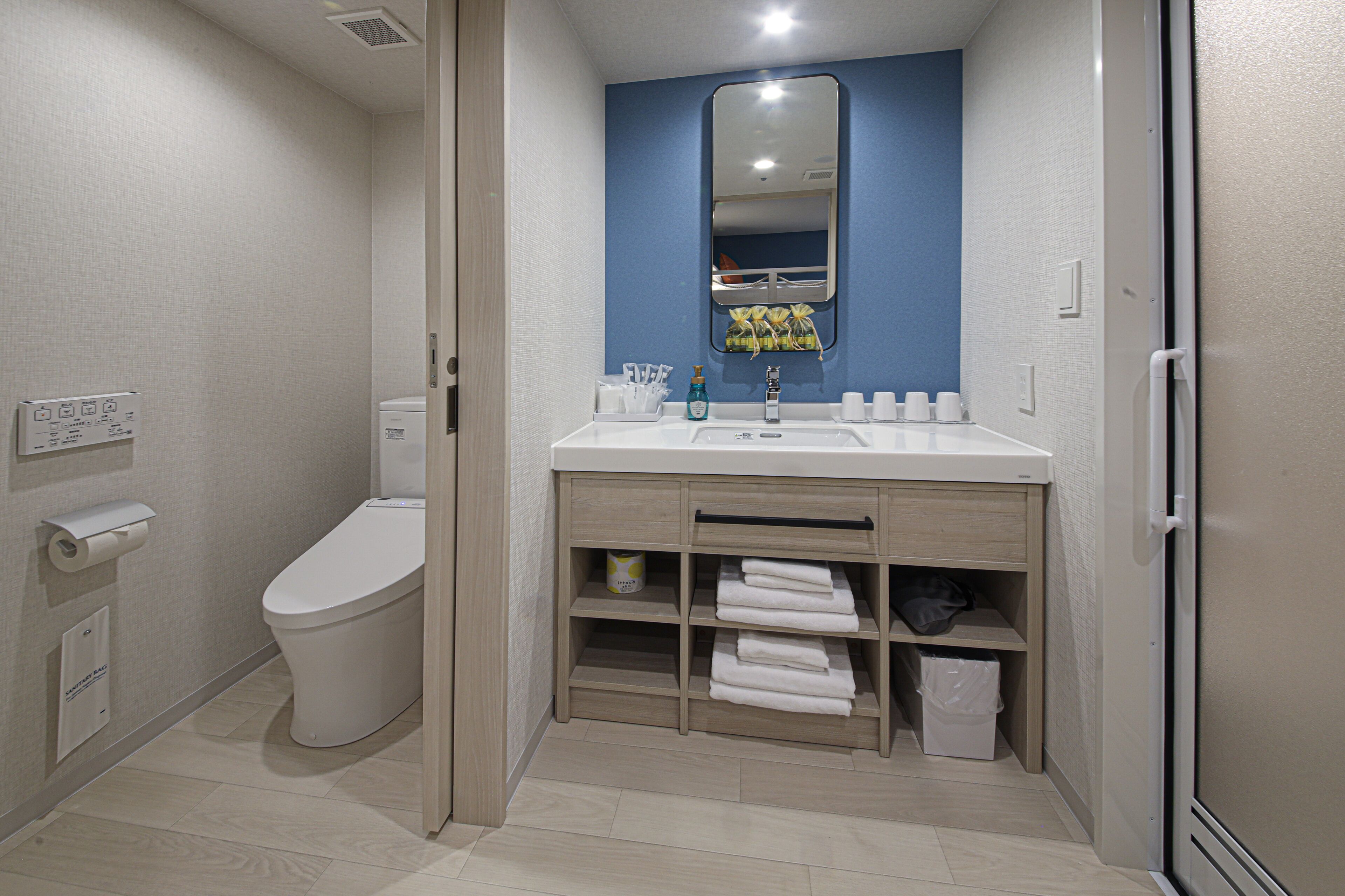 A modern bathroom with a toilet, sink, and mirror.