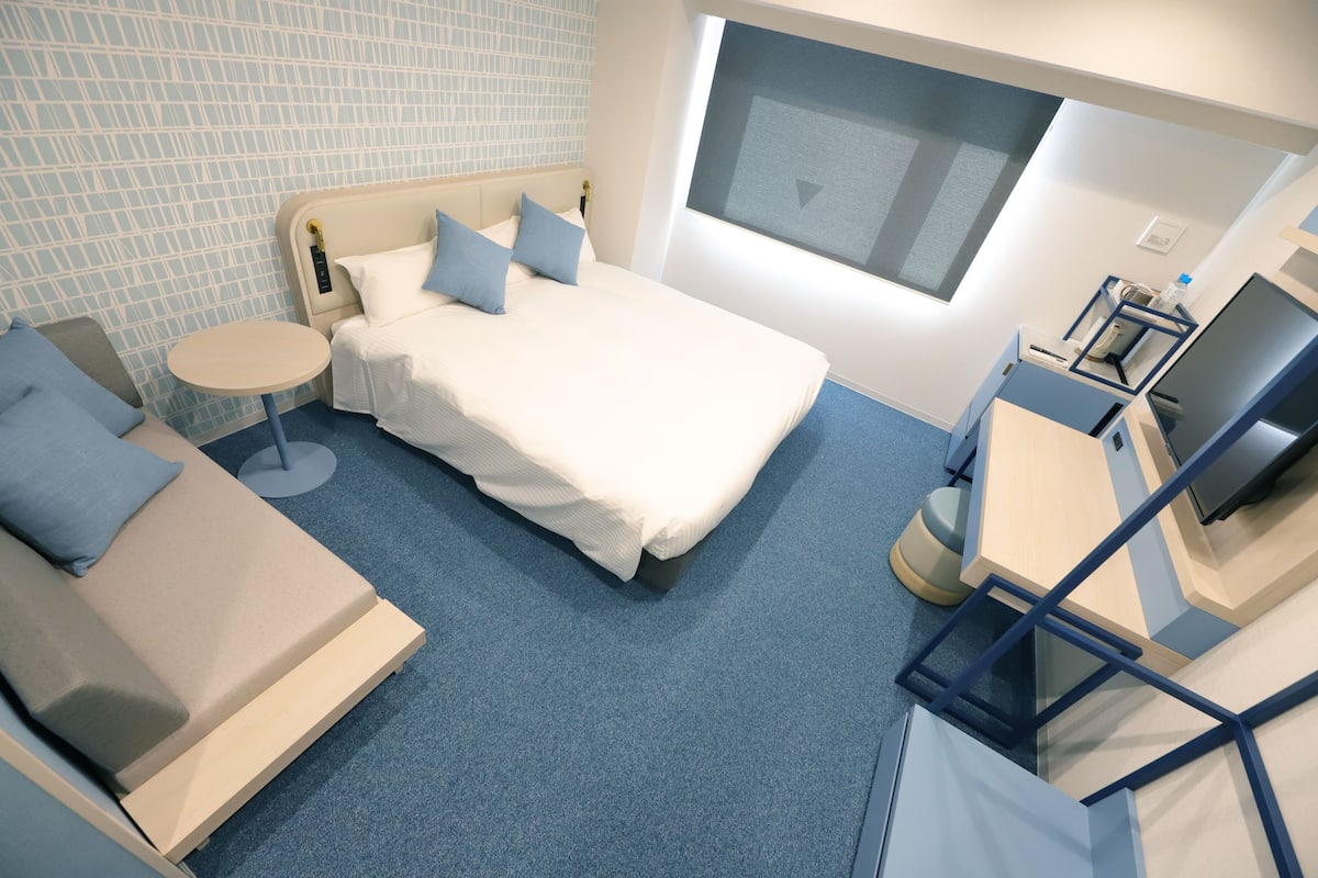 Une chambre d’hôtel moderne équipée d’un lit, d’un canapé, d’une petite table ronde et d’un téléviseur.