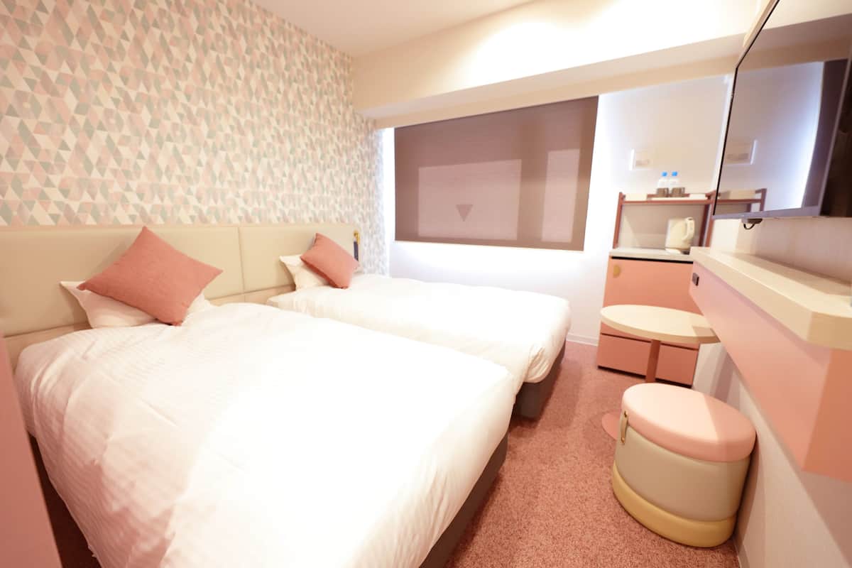 Une chambre d’hôtel avec deux lits, une petite salle de bain et un grand miroir.