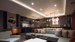 A modern living room with a sofa, armchair, and coffee table, a kitchen area, and a dining space. - Spa World (Osaka)