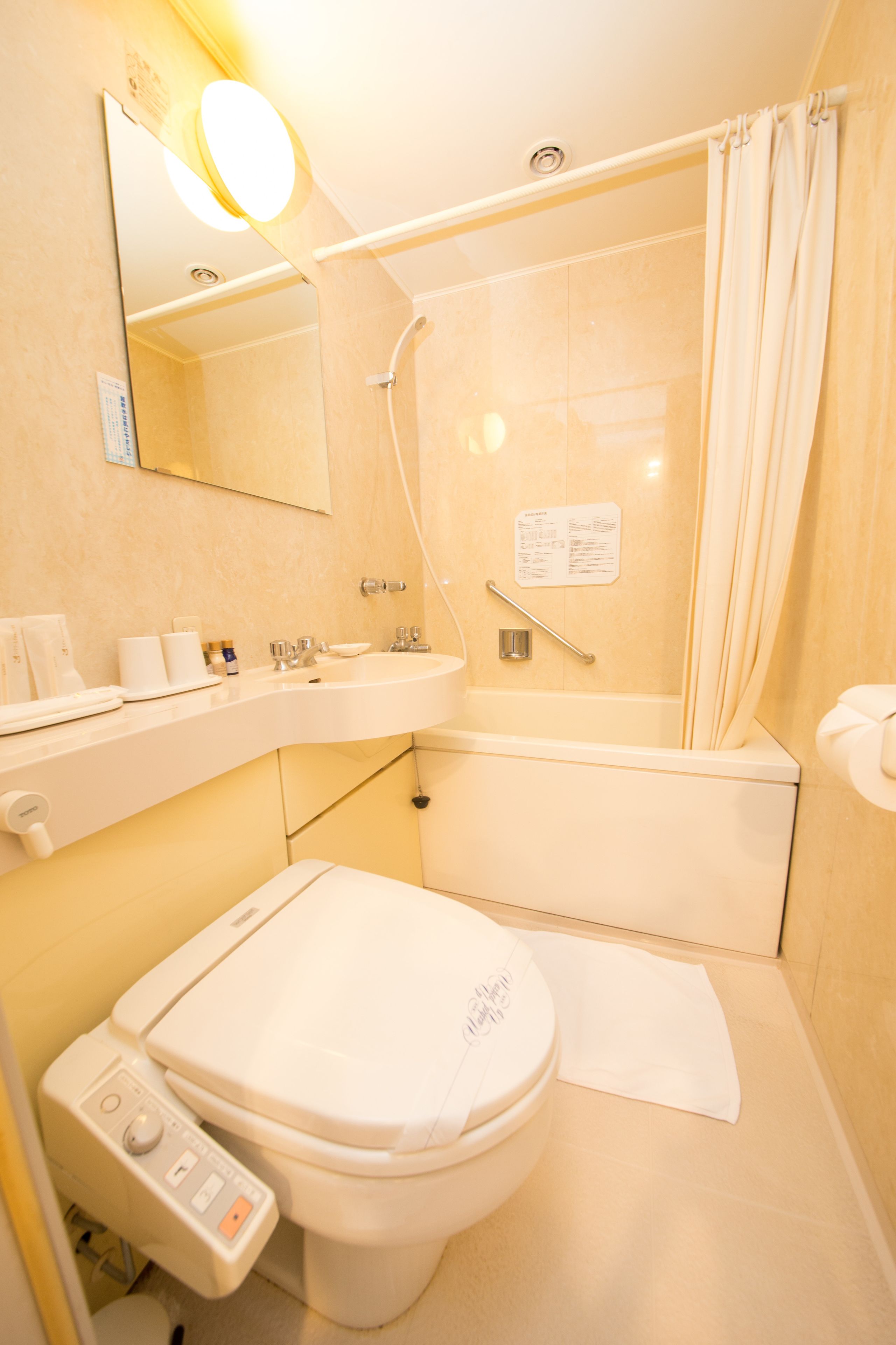 A bathroom with a toilet, sink, mirror, shower, and a towel rack.