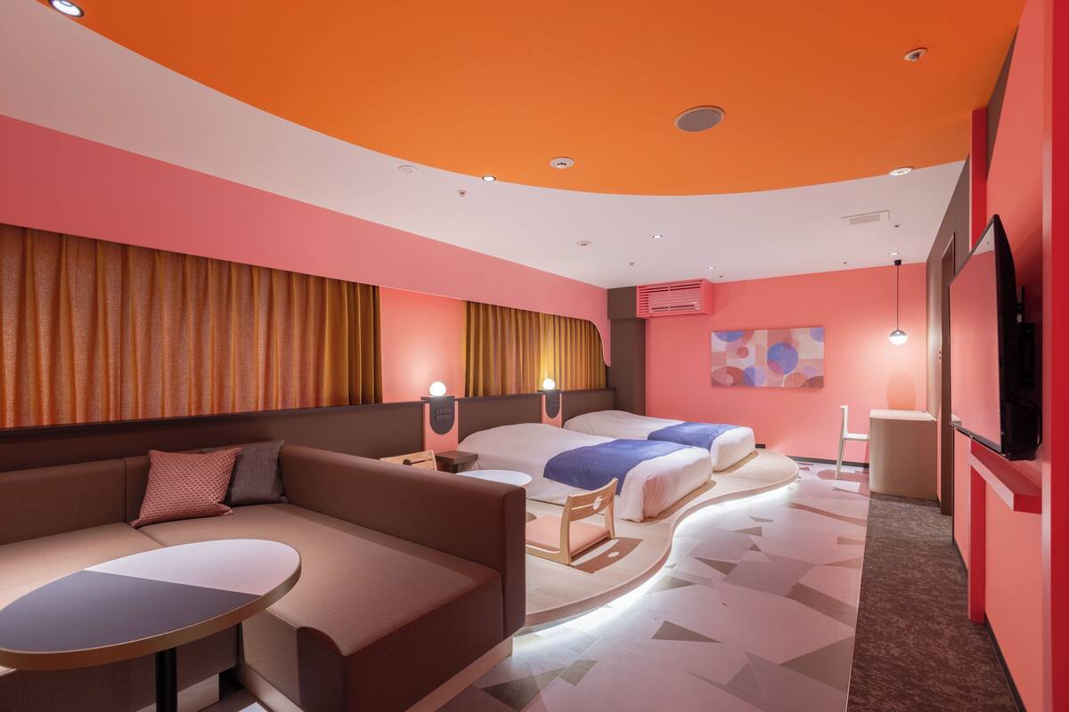 Une chambre d’hôtel moderne avec un plafond incurvé, un canapé, un lit, une petite table et un téléviseur.