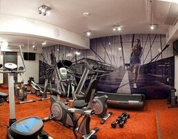 Uma academia com diversos equipamentos de exercícios, incluindo esteiras, bicicletas ergométricas e pesos.