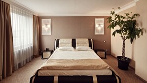 A hotel room with a large bed, two bedside tables, a potted plant, and a window with curtains. - M Hotel Sosnowiec (Sosnowiec)