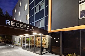 A modern hotel entrance with a reception desk, glass doors, and a sign reading "RECEPTION". - M Hotel Sosnowiec (Sosnowiec)
