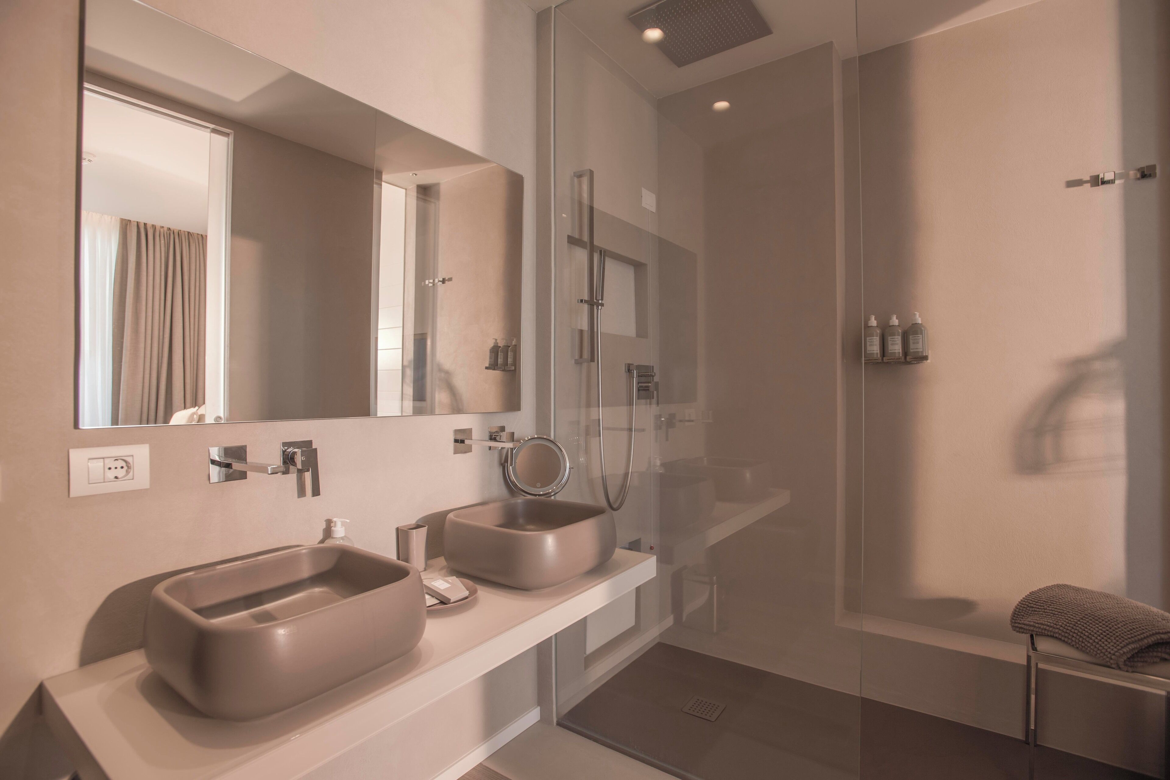 A modern bathroom with two sinks, a glass-enclosed shower, and a large mirror.